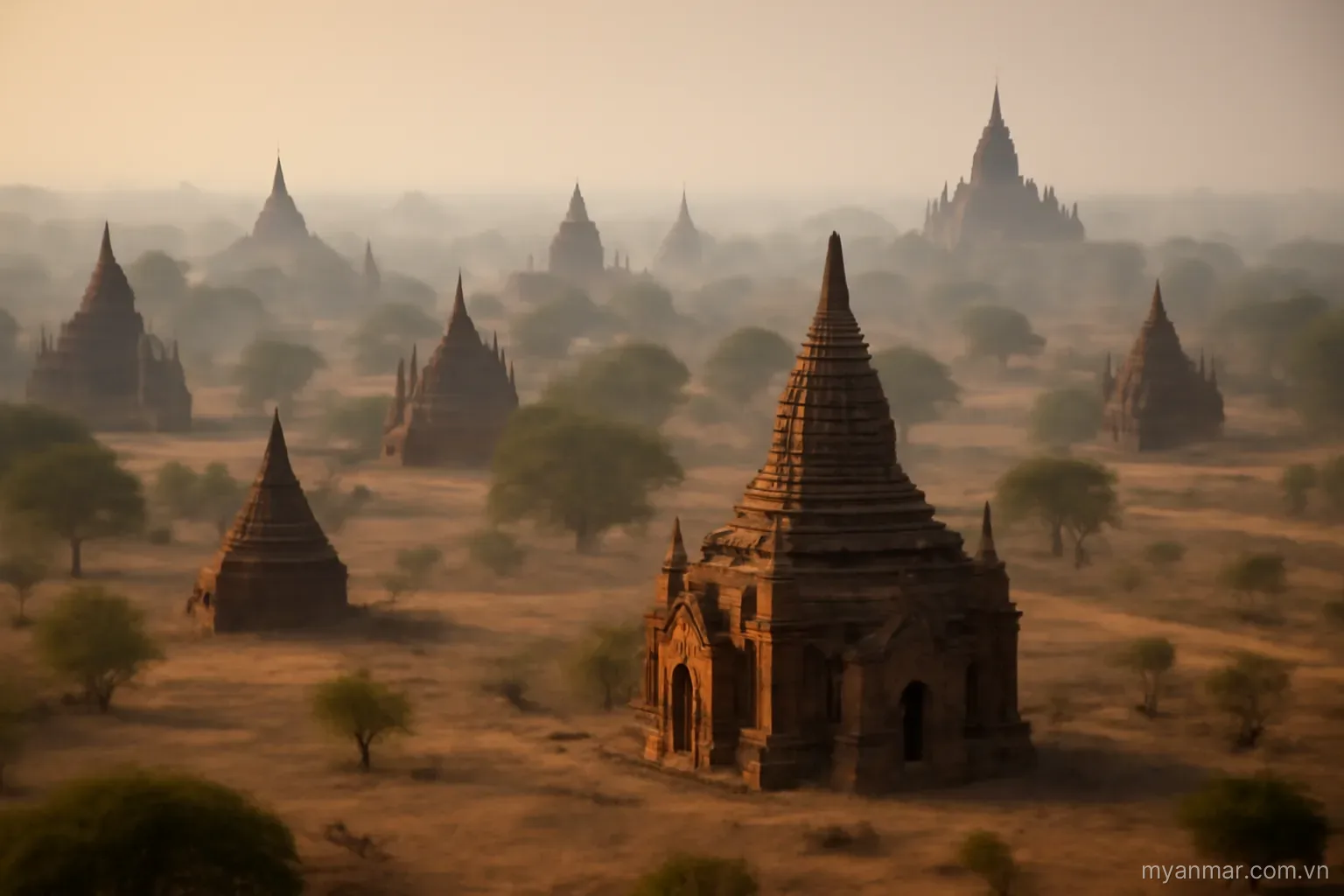 Many brick temple spires scattered across a dry plain in morning haze, aerial view, no text