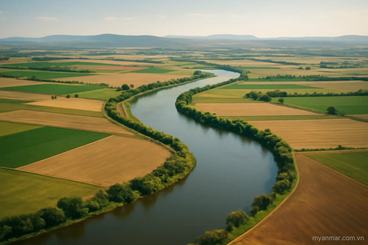 A wide river winding through flat farmland with distant hills, aerial view, no text