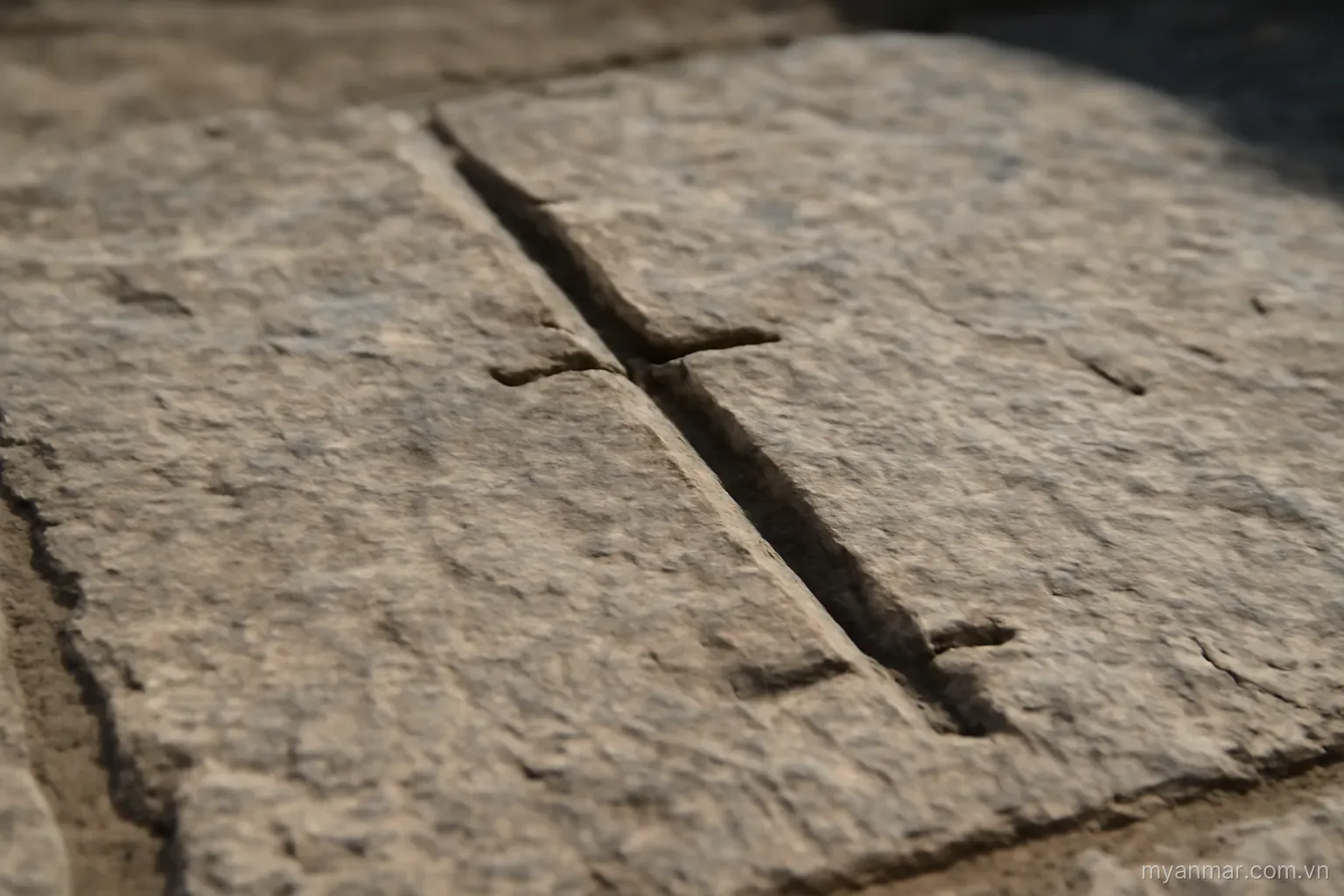 A single long groove running the length of a stone slab with short side grooves branching off, overhead, no text
