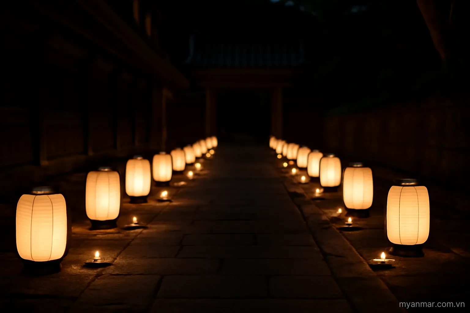 Paper lanterns and candles lit along a temple walkway at night, wide view, no text