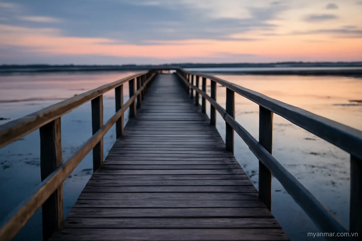 A long wooden footbridge stretching across shallow water at dusk, wide view, no text