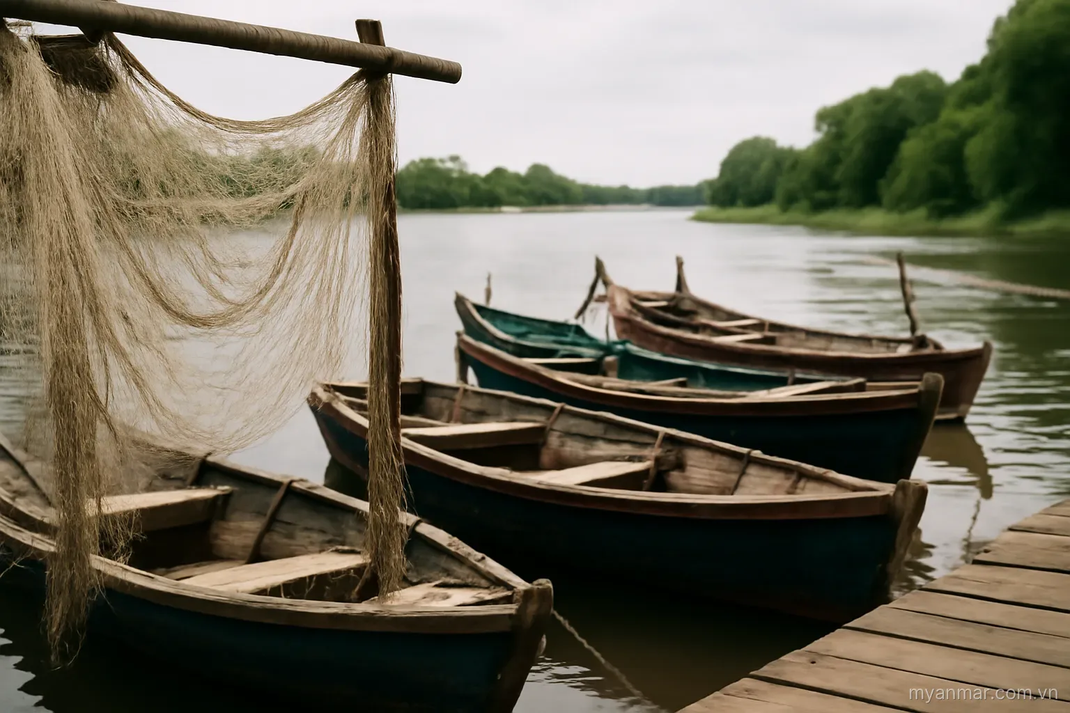 Wooden fishing boats moored at a river jetty with nets drying, wide view, no text
