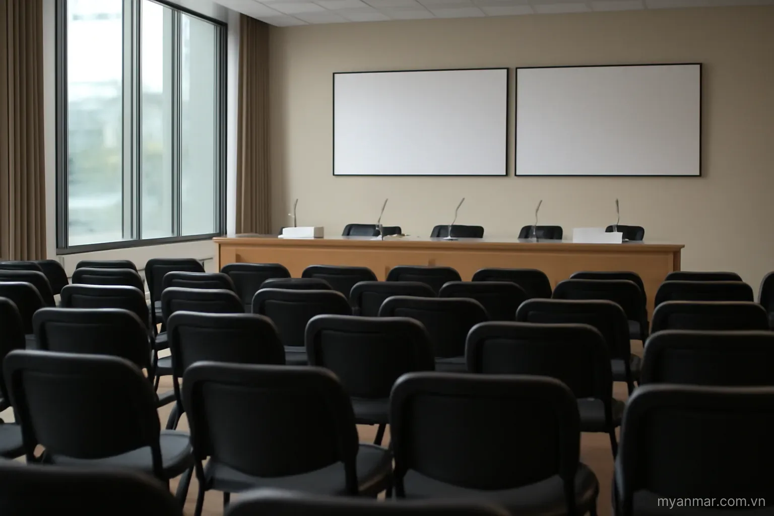 A conference hall with rows of empty chairs and a long table, wide view, no text