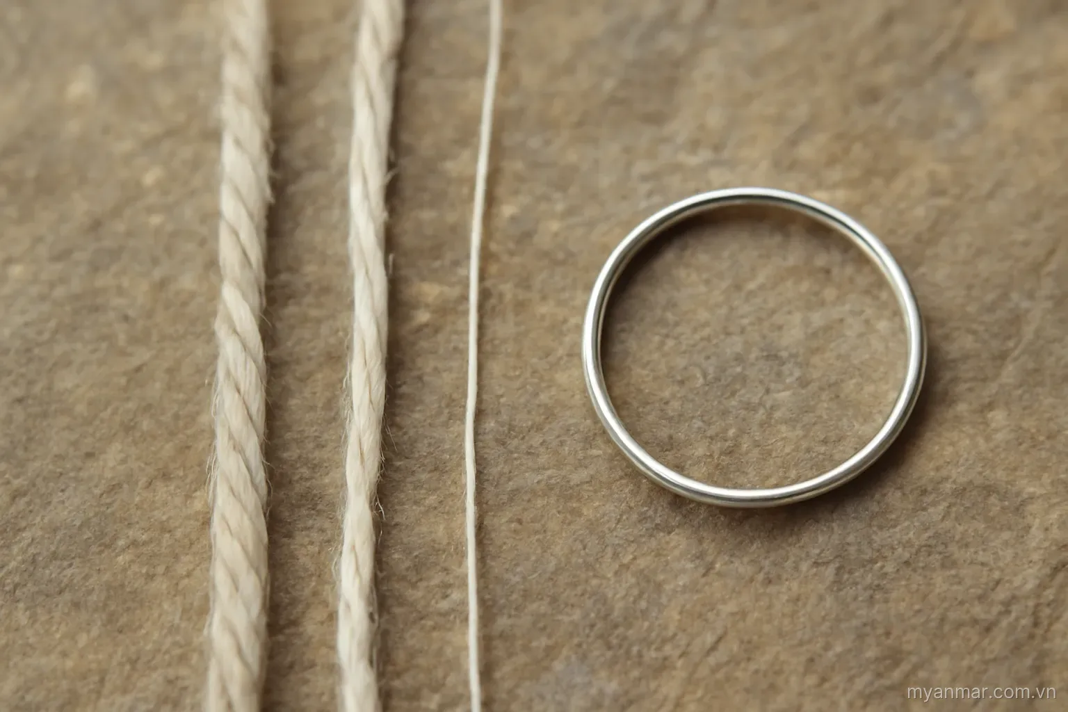 Threads of three different thicknesses beside a single narrow ring, close view on stone, no text