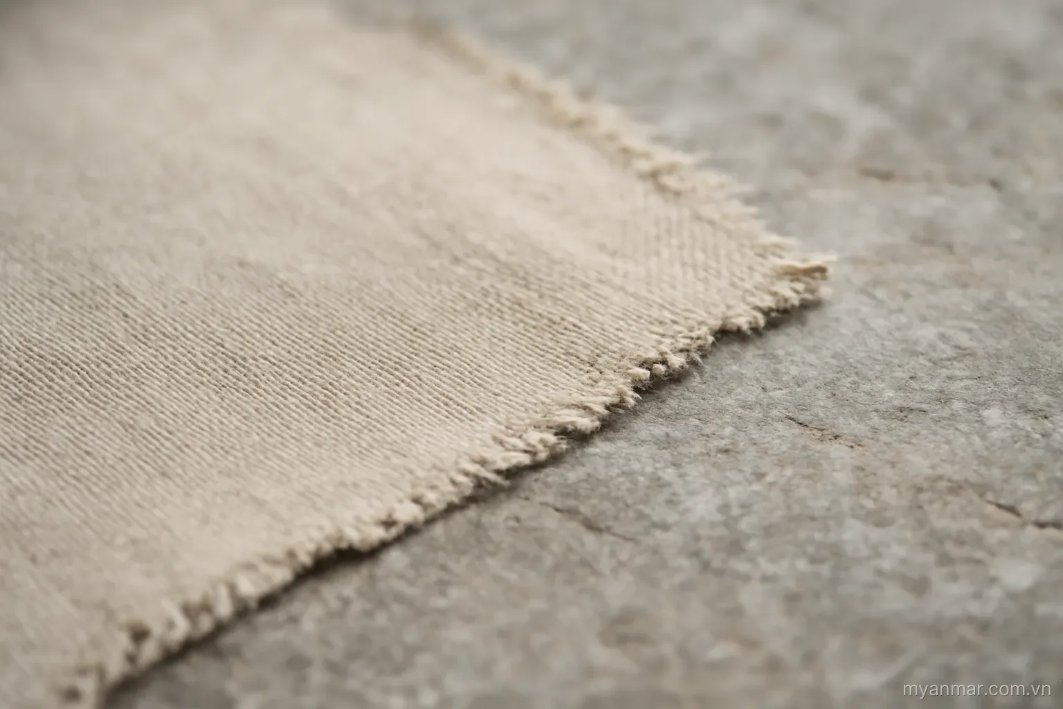 A woven cloth with an irregular edge pattern lying flat on stone, close view, no text