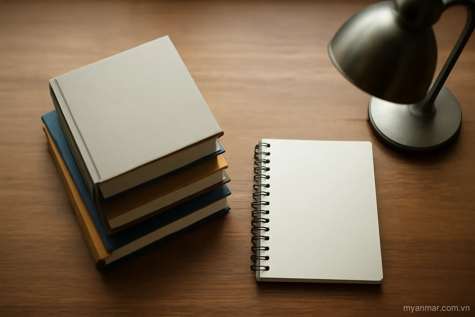 A stack of books and a notebook beside a desk lamp, top-down view, no text